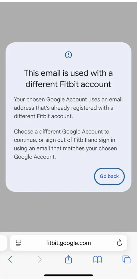 A phone browser on fitbit.google.com showing the message This email is used with a different Fitbit account, saying the chosen Google Account uses an email address already registered with a different Fitbit account, with a Go back button.